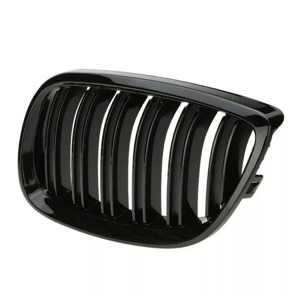 A shiny, black automotive grille with vertical slats is lying on a plain, white background, likely for use as a vehicle front intake or trim component.