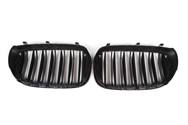 Two black car grille inserts with vertical slats lie side by side against a white background, designed to fit into a vehicle's front end for ventilation.