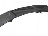 A curved carbon fiber car spoiler rests on a flat surface. The piece features aerodynamic design elements, such as a high-gloss finish and multiple support fins.
