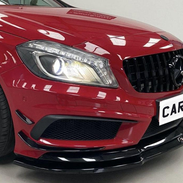 Red car with illuminated headlight shines in indoor lighting, featuring a black grille and a visible tire. The license plate reads "CAR" on a white background.