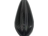 Black carbon fiber object, shaped like a teardrop, featuring aerodynamic grooves. It appears to be a vehicle part, possibly a motorcycle seat cover, set against a plain white background.