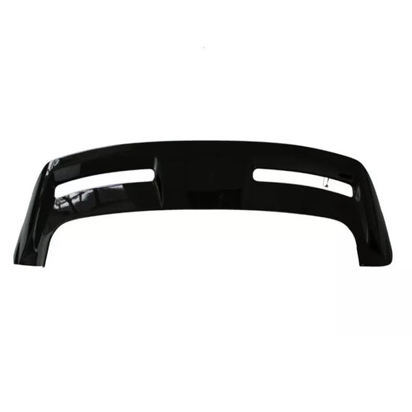 A black automotive bumper with two elongated cutouts lies on a plain, white background, showcasing its smooth surface and contoured design.