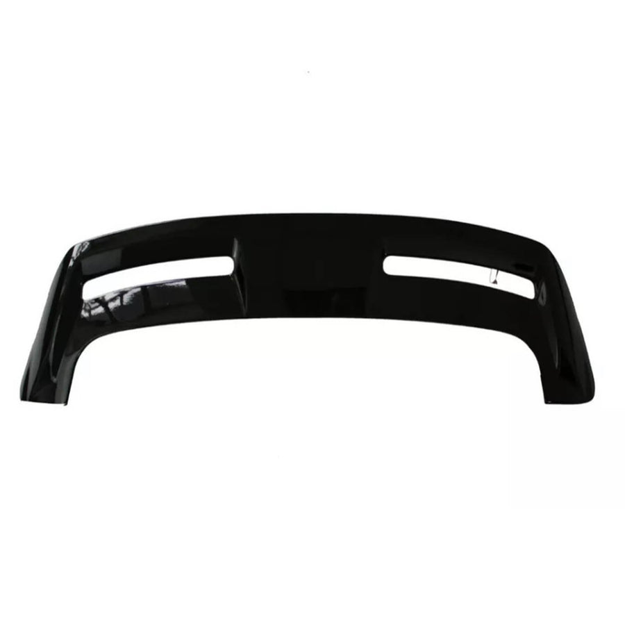 A black automotive bumper with two elongated cutouts lies on a plain, white background, showcasing its smooth surface and contoured design.