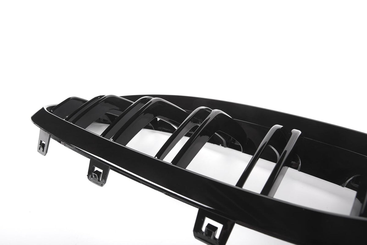 A black car grille features horizontal slats with connectors, set against a white background, highlighting its glossy finish and sleek design.