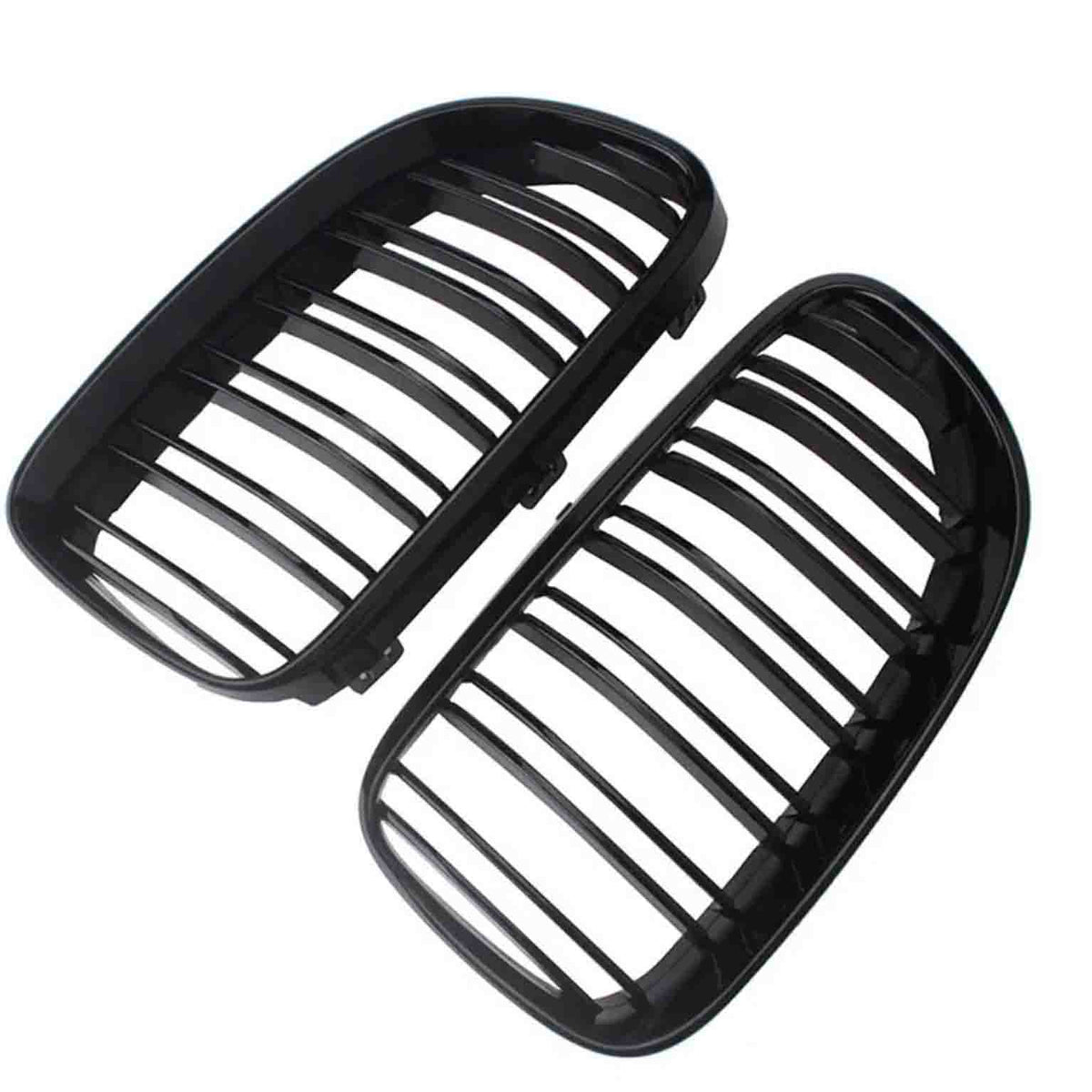 Two black car grille inserts, featuring vertical slats, lie angled against a white background. They are separated, showing both the front and back view of each grille.