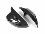 Two glossy carbon fiber mirror covers are displayed on a white background, highlighting their sleek, aerodynamic design and texture.