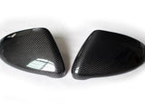 Two carbon fiber car side mirror covers lying on a white surface, displaying a sleek, glossy pattern with no visible text.