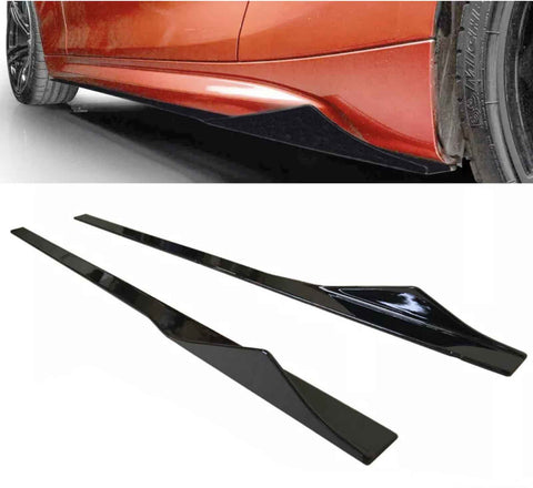 Two glossy black side skirts lie on a white surface, designed for a vehicle shown partially in orange above with one already installed near its tire.
