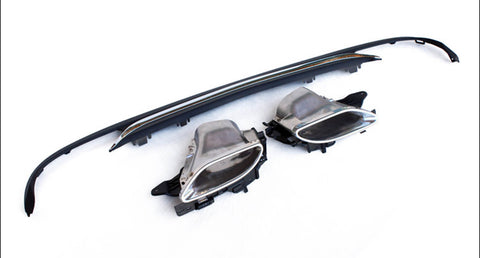 Car exhaust tips and diffuser lie on a white surface, highlighting their metallic and plastic construction. The exhaust tips show a chrome finish, while the diffuser is black and elongated.