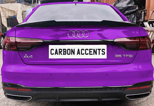 A purple Audi A4 with "35 TFSI" badge is parked, displaying the license plate text "CARBON ACCENTS." The vehicle is in a workshop area with various items in the background.