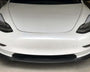 A white car is parked in a garage, focusing on its sleek front design with prominent headlamps and a smooth bumper.