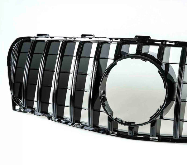 A black car grille features vertical slats and a central circular frame. It is positioned against a plain white background, highlighting its glossy surface and geometric design.