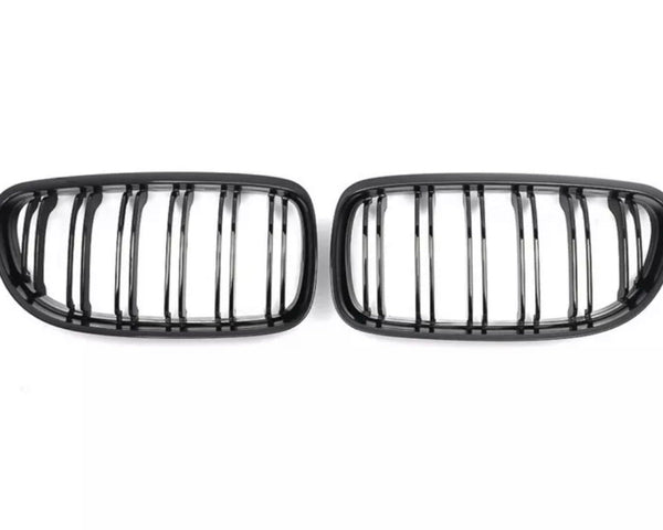Two black, oval grilles with vertical slats are positioned side by side on a plain white background.