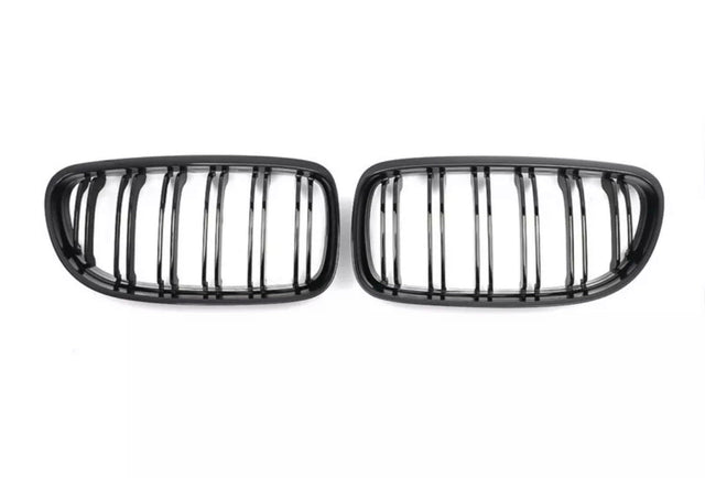 Two black, oval grilles with vertical slats are positioned side by side on a plain white background.