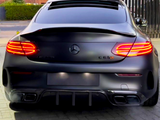 A black Mercedes-Benz C 63 S AMG is parked, with illuminated tail lights, on a paved driveway. Houses and a black metal fence are visible in the background.