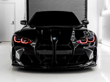 A sleek black BMW with illuminated red headlights is parked in a white room in front of a metal shutter door. An 