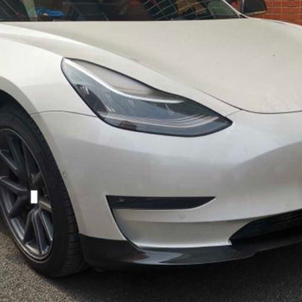 White car with sleek design parked beside brick wall; "CARBON ACCENTS" text on license plate; black rims and tinted windows complete its modern appearance.