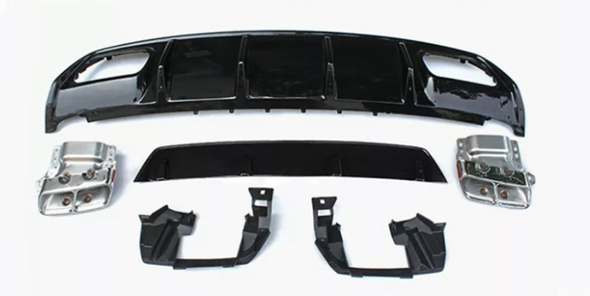 Assorted car parts, including a large black bumper and metallic components, are laid out on a plain white surface, arranged neatly for display or assembly.