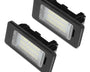 Two rectangular LED lights are placed side by side, featuring black casings and transparent panels with visible bulbs, against a plain white background.