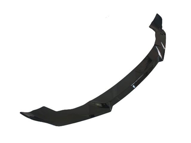 A glossy black car front splitter, designed to enhance aerodynamics, lies against a plain white background.