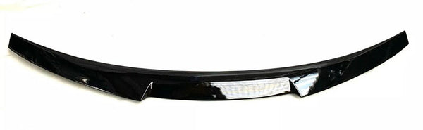 A black car spoiler with a glossy finish is positioned horizontally on a plain white background. The design is sleek, slightly curved, and features a central reflective strip.