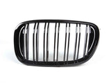 A shiny black car grille with vertical slats is displayed against a plain white background, emphasizing its sleek design.