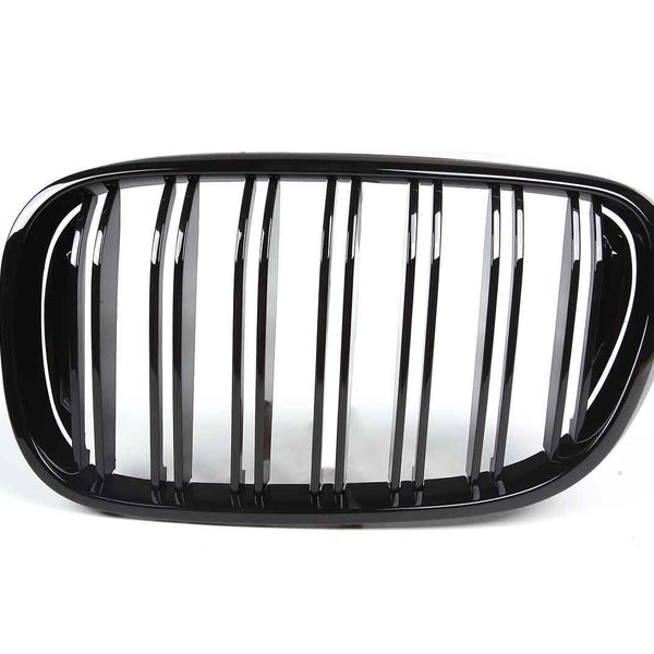 A shiny black car grille with vertical slats is displayed against a plain white background, emphasizing its sleek design.