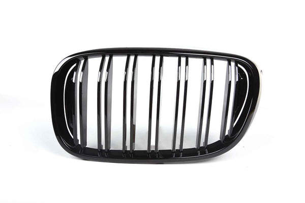A shiny black car grille with vertical slats is displayed against a plain white background, emphasizing its sleek design.