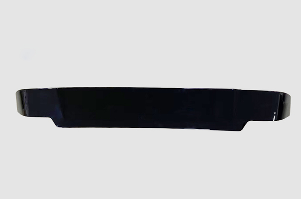 A sleek, black, elongated object lies horizontally, possibly an automotive spoiler or similar accessory, set against a plain light gray background.