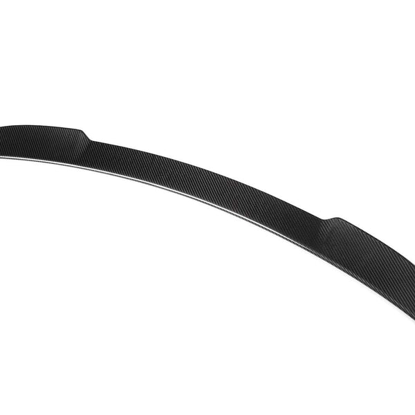 A black carbon fiber car spoiler, shaped with a sleek, aerodynamic curve, rests isolated against a plain white background.