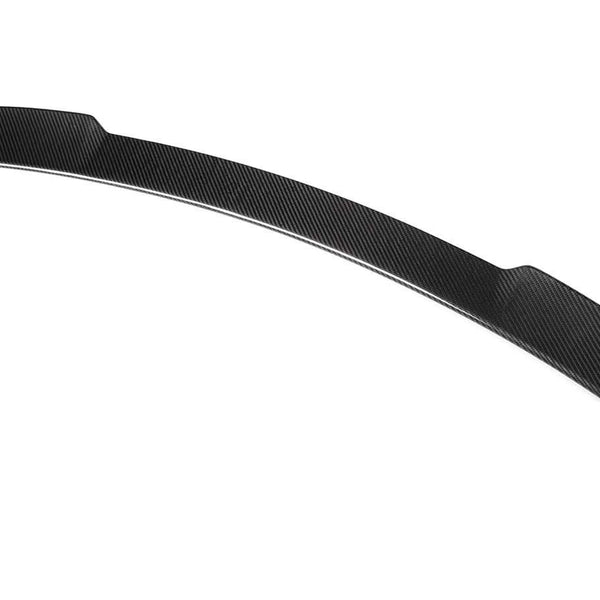 A carbon fiber car spoiler features a sleek, curved design, resting against a plain white background.