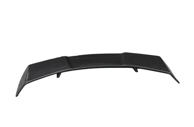 A black car spoiler slightly curved upwards, positioned on a plain white background. The surface has a textured pattern, indicating a potential carbon fiber material.