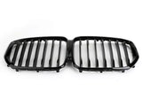 A black, dual kidney-shaped car grille features vertical slats, designed for a vehicle's front end. It rests against a plain white background, emphasizing its sleek design.