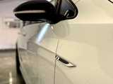 A close-up of a white car's side, featuring a black side mirror and an 