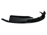 A glossy black car bumper lip rests against a white background, showcasing its aerodynamic design with sharp edges and smooth curves.