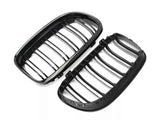 Black car grilles lie side by side, featuring vertical slats within oval frames, presented on a white background.