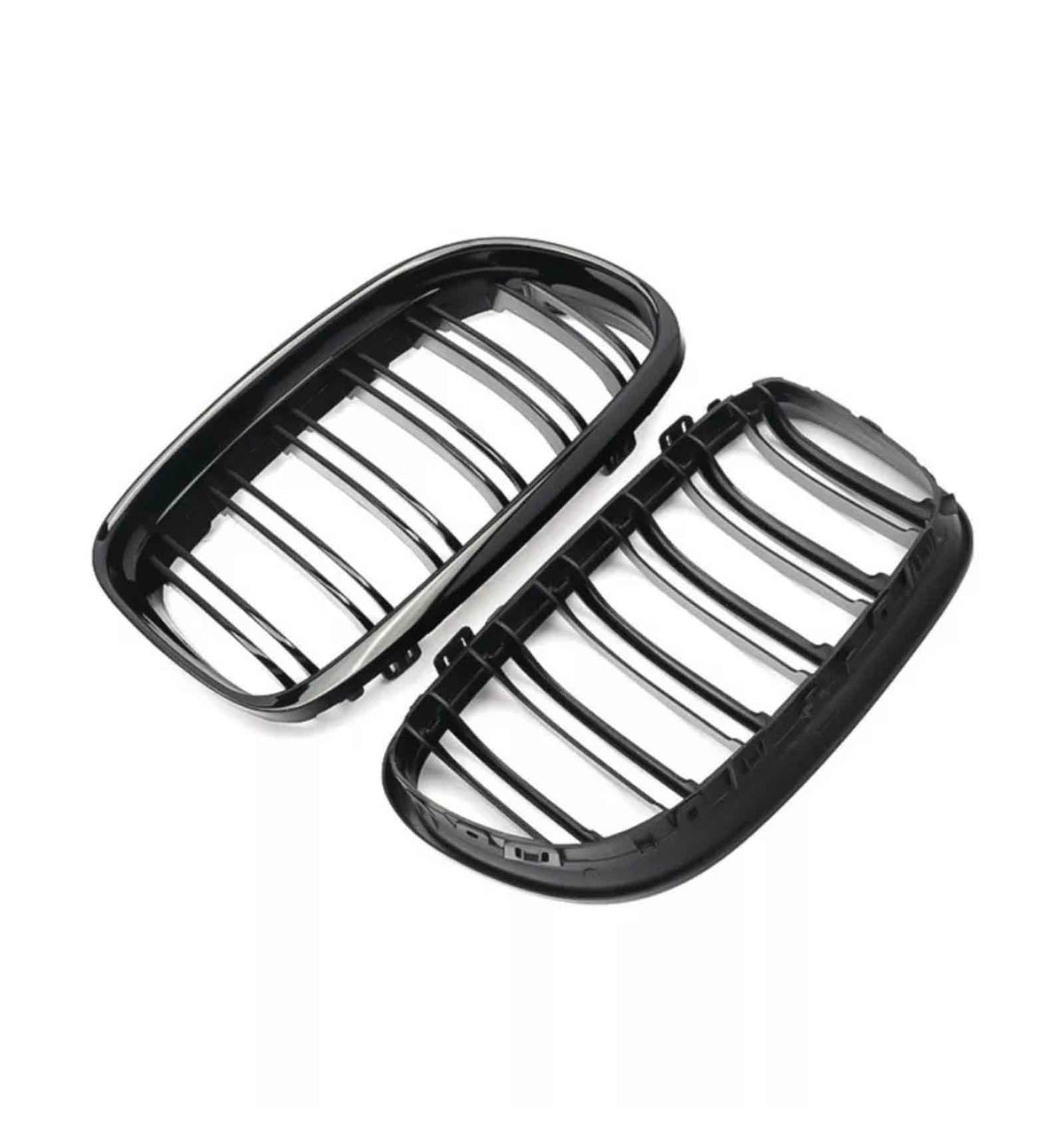 Black car grilles lie side by side, featuring vertical slats within oval frames, presented on a white background.