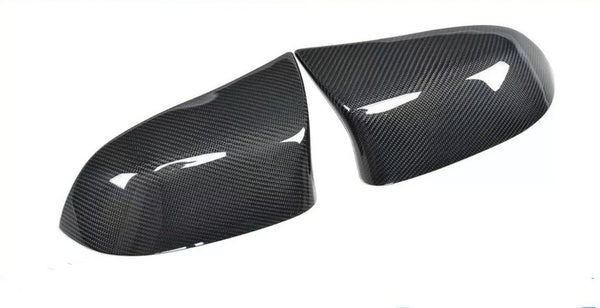 Carbon fiber car mirror covers, positioned side by side, displaying a glossy surface with visible texture, set against a plain white background.