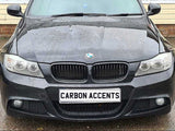 A black BMW car with water droplets on the hood is parked. The license plate reads 