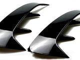 Two sleek, black, curved automotive fins with angular protrusions are positioned side by side on a plain white background, emphasizing their glossy finish and aerodynamic design.