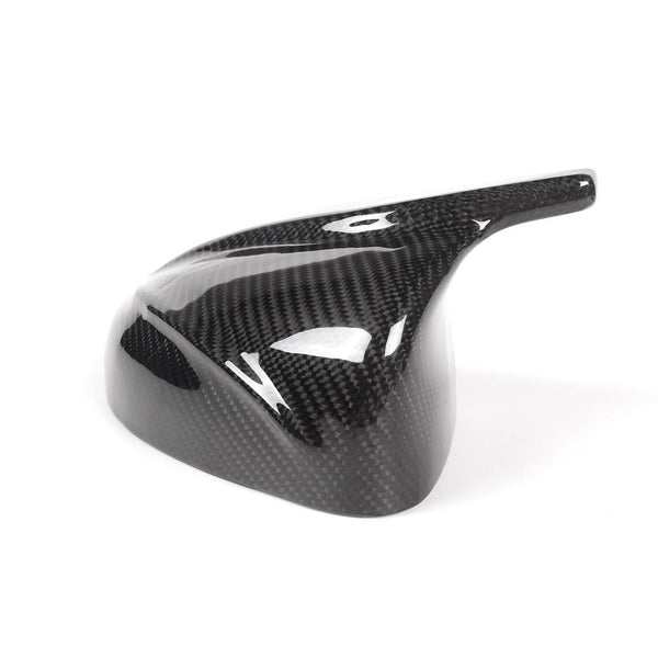 A glossy, black carbon fiber vehicle mirror cover is placed on a plain white background, showcasing its sleek, aerodynamic design and lightweight material.