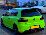 A bright green Volkswagen hatchback is parked in a residential street, displaying 