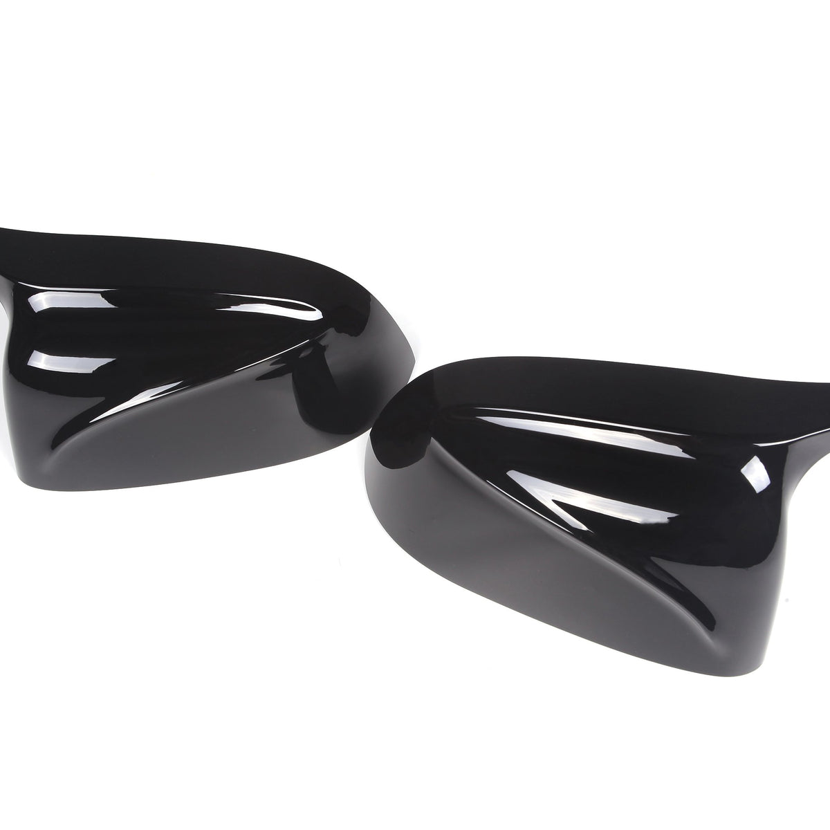 Two glossy, black car side mirror covers lie side by side on a plain white background, showcasing a sleek and aerodynamic design.