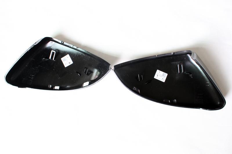 Two black plastic car mirror covers lie open on a white surface, with stickers displaying product information on each cover's interior.