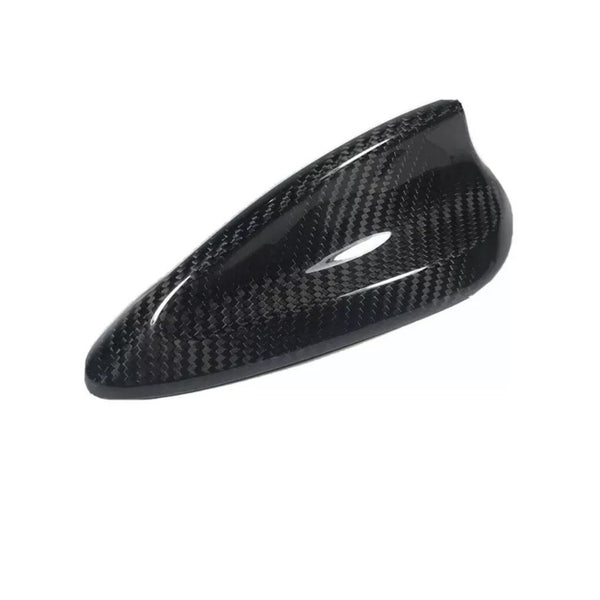 Carbon fiber car mirror cover; sleek and glossy, with a textured, woven pattern reflecting light. The cover rests against a plain white background, emphasizing its aerodynamic design.