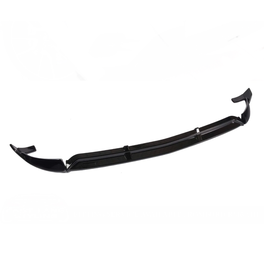 A black front lip spoiler, designed for automotive use, is displayed on a plain white background. It features aerodynamic contours with upward-curved edges, suggesting it is for enhancing vehicle aerodynamics.