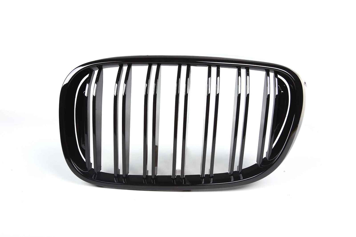 A shiny black car grille features vertical slats framed by an oval shape, set against a plain white background.