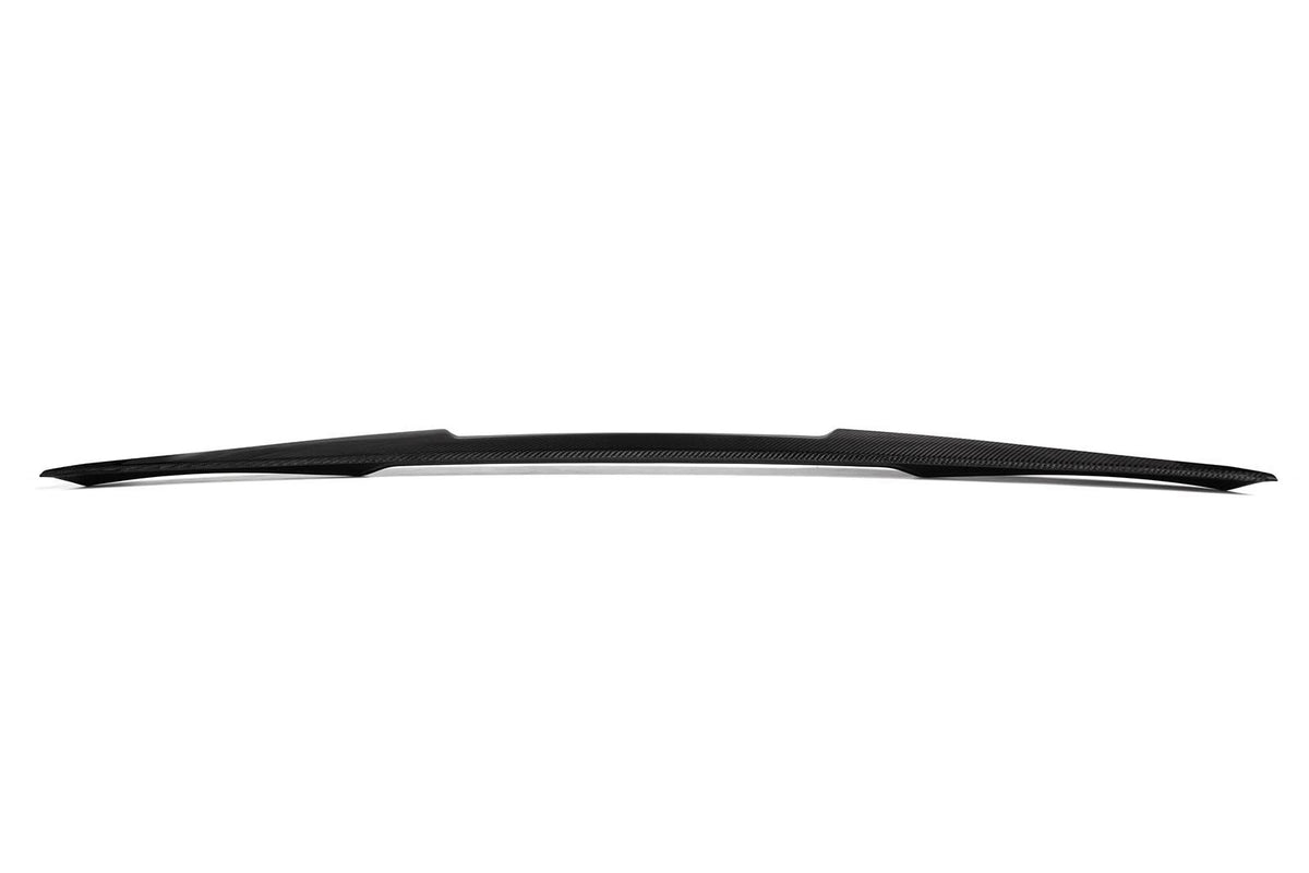 A sleek, black carbon fiber car spoiler with a slight curve sits against a plain white background, showcasing its aerodynamic design.