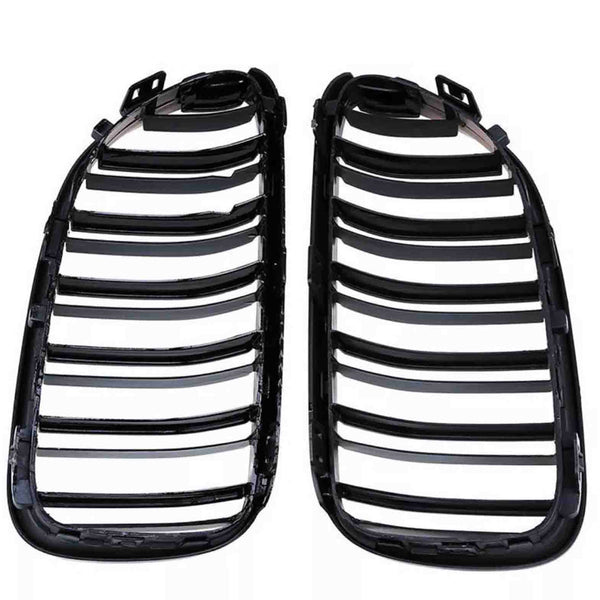 Two black plastic car grille inserts lie side by side, featuring multiple horizontal slats, against a plain white background.
