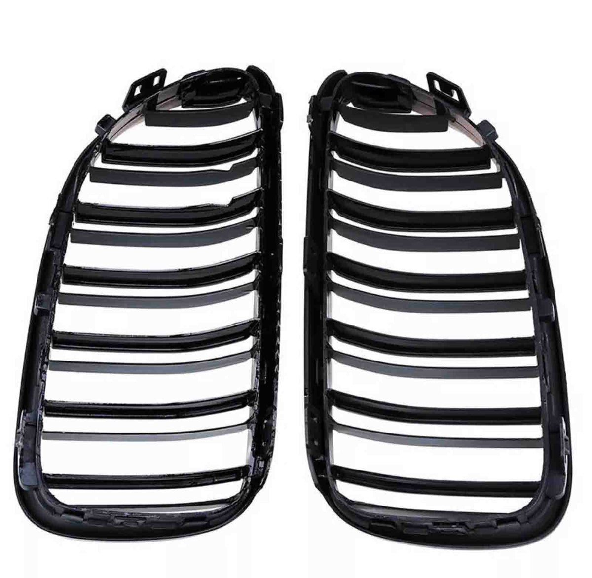 Two black plastic car grille inserts lie side by side, featuring multiple horizontal slats, against a plain white background.